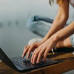 woman sitting on bench browsing laptop